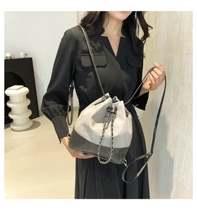 Close-up of a color-block bucket bag featuring silver chain drawstring and adjustable strap