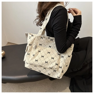Detail view of corduroy tote bag featuring black quilted diamond pattern and bow accents
