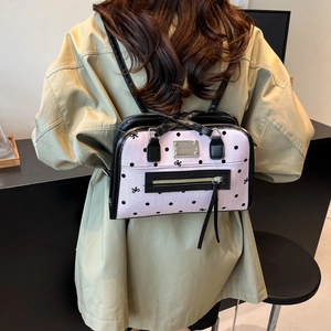 Pink polka dot backpack with bow patterns and black straps shown on a model