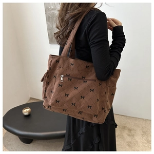 Detail view of brown corduroy tote bag featuring black bow patterns and quilted texture
