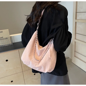 Back view of light pink hobo bag with chain detail on a model in a modern interior