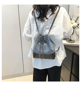 Detail of blue denim bucket backpack with chain accent and black leather patchwork