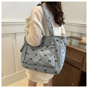 Blue corduroy tote bag with black bow print and large front pocket on shoulder