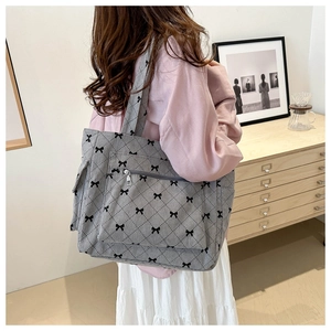 Gray corduroy tote bag detail with black bow embroidery and convenient front zipper pocket