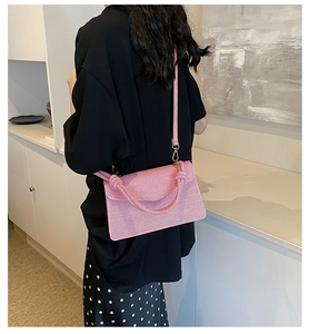 Detail of pink woven crossbody bag with knotted handle and detachable shoulder strap