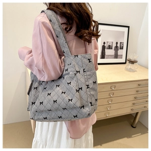Detailed view of the checkered tote bag side pocket with black bow print and corduroy texture