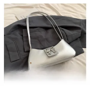 Sac sous le bras argenté en forme de croissant avec nœud sur veste de costume