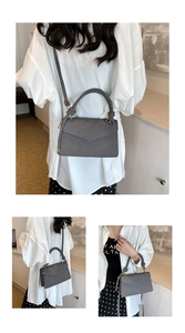 Detail of dark gray crossbody bag showing twill fabric texture and golden metal fastener