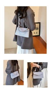 Detail of light blue tweed crossbody bag featuring a knot handle and golden hardware