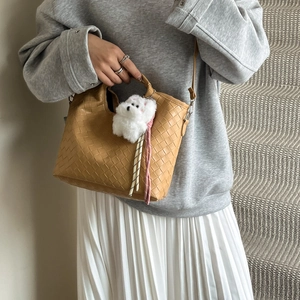 Camel woven bucket bag with teddy charm and shoulder strap on grey casual outfit