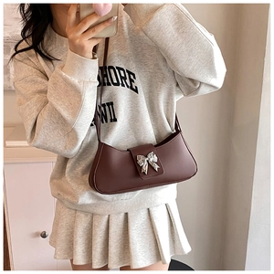 Détail du sac sous l'aisselle en cuir marron foncé avec boucle papillon argentée