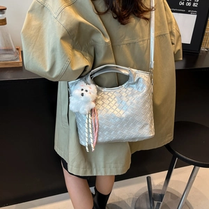 Silver woven bucket bag with dog charm and crossbody strap shown in lifestyle setting