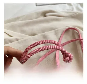 Detailed macro view of pink braided rope handle with golden metal hook on handbag