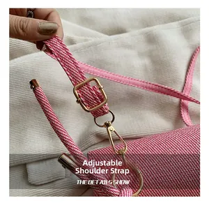 Detail of adjustable shoulder strap with gold buckle on pink woven texture crossbody bag