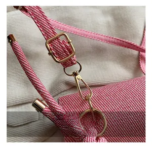 Detailed macro view of woven red and white bag strap with premium gold metal buckles