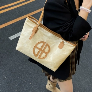 Grand sac cabas beige avec bordure en cuir marron et logo rond pour trajet quotidien