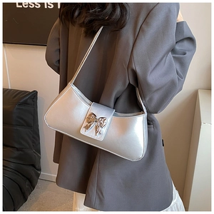 Vue détaillée du sac baguette argenté avec un nœud papillon en métal chic et brillant