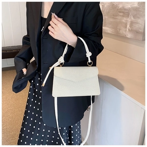 Detail of cream white envelope crossbody bag with knot handle and golden ring hardware