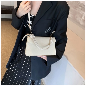 Detail of cream square crossbody bag with woven texture and knotted handle feature