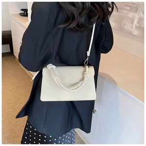 Back view of a woman wearing the beige woven crossbody bag with a thick rope handle