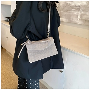 Detail of champagne woven crossbody bag with envelope flap and knotted strap on model