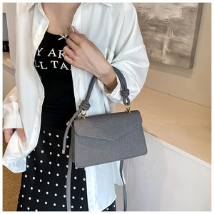 Detail of grey twill crossbody bag with unique woven rope handle and gold metal hardware
