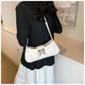Détail du sac à bandoulière blanc avec un ornement en métal en forme de papillon argenté