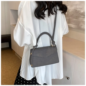 Detail of grey twill envelope handbag with gold metal buckles and top handle