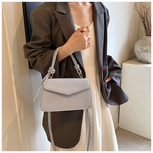 Detail of light grey crossbody bag with rope braided handle and elegant knot design