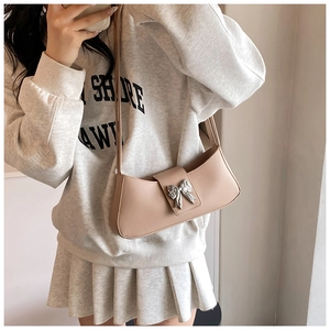 Détail d'un sac à bandoulière en similicuir beige avec une boucle papillon argentée