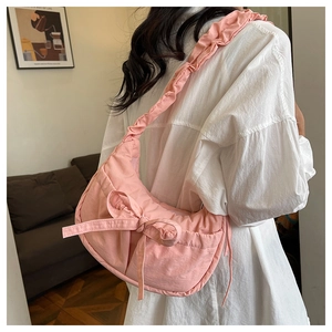 Pink crescent crossbody bag with large bow and ruffled shoulder strap on model