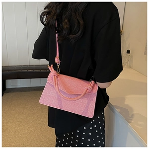 Detailed view of pink woven textured crossbody bag with a thick knotted top handle