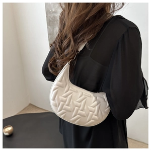 Detailed view of white crescent bag with embossed texture and gold metal hardware link