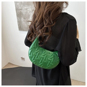 Detail of green crescent moon bag with 3D padded woven texture and slender shoulder strap