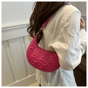 Detail of fuchsia half-moon shoulder bag with geometric quilted texture on white blazer