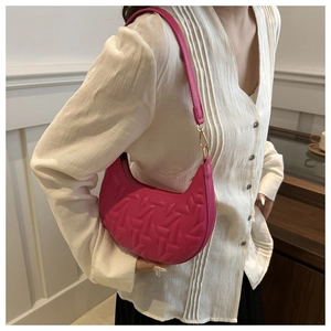 Detail of fuchsia crescent bag featuring 3D embossed texture and slim shoulder strap