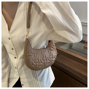 Detail of beige crescent bag featuring woven geometric texture and golden hardware