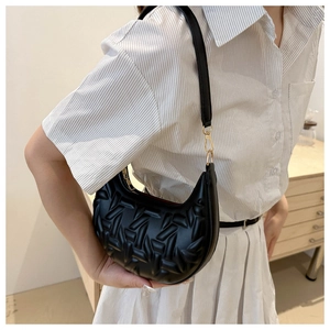 Detail of black crescent shoulder bag with geometric embossed texture and gold metal clasp