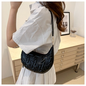 Detail of black crescent hobo bag featuring geometric quilted texture and gold hardware