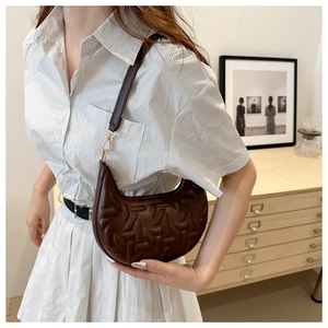 Detail of dark brown crescent underarm bag showing geometric embossed texture and hardware
