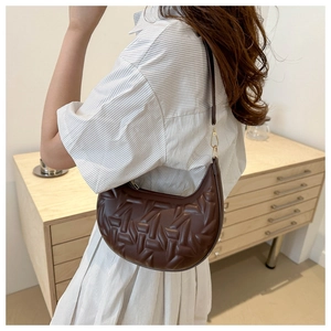 Detail of dark brown hobo bag featuring quilted woven texture and gold hardware