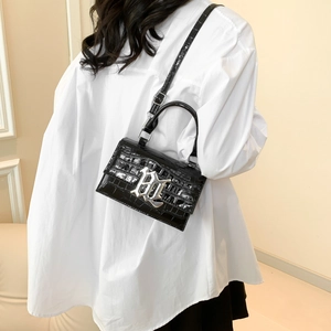 Glossy black croc-effect small square handbag with silver metal buckle on a white shirt