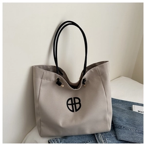 Detalle del bolso tote de lona taupe con un logotipo negro y asas de cuerda fina