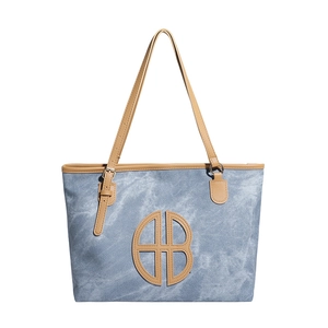 Large blue patchwork tote bag with brown leather straps and cutout logo detail