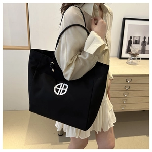 Detalle del bolso tote grande de lona negra minimalista con logo gráfico blanco