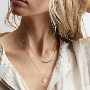 Zweilagige Goldhalskette mit Perlenkette und minimalistischem Münzanhänger an Model