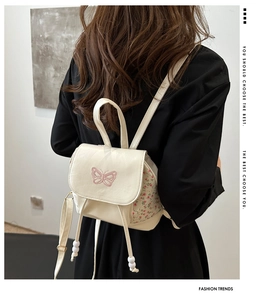 Detail of mini cream backpack with butterfly embroidery and pink floral drawstring