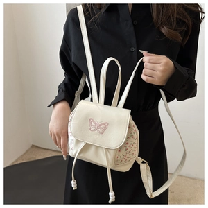 Detail of cream backpack with pink butterfly embroidery and floral side panels