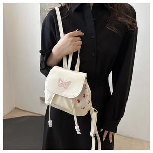 Mini cream drawstring backpack featuring pink butterfly embroidery and cherry prints