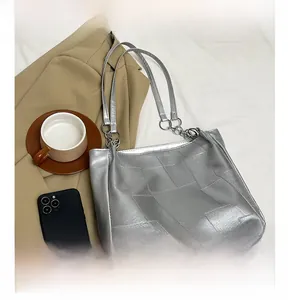 Close-up of silver-gray tote bag with woven texture and metallic chain strap